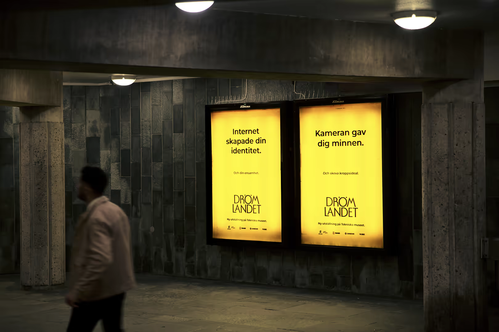 Two Drömlandet posters lit up on digital screens in the Stockholm metro